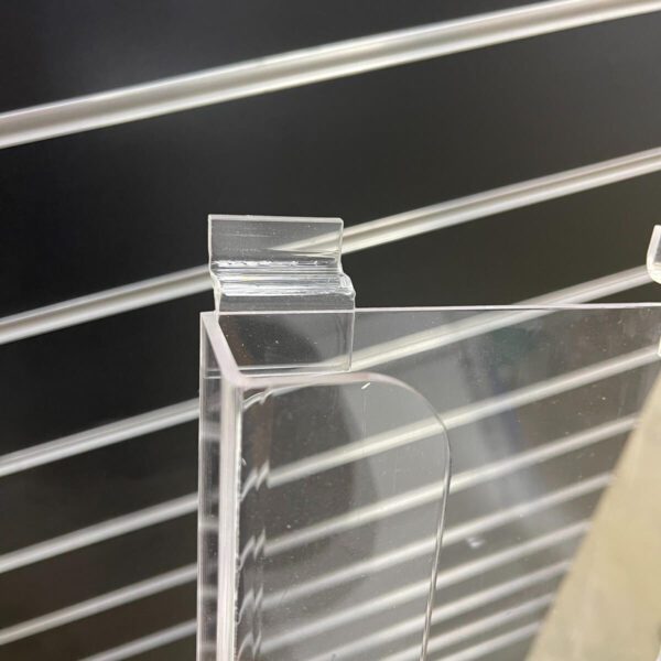 this image shows the acrylic slatwall fitting that is attached to the a4 brochure holder, there is black slatwall in the background.