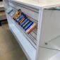 sloping acrylic shelf on a white shop counter holding chocolate bars and cans of drink.