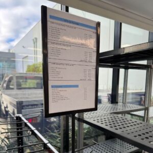 black frame A4 sign holder sitting on black shelving unit